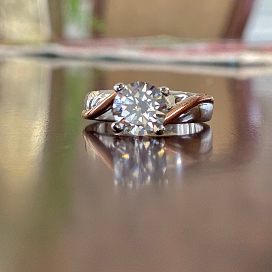 Elegant criss-cross diamond engagement ring with round-cut diamond and mixed gold band.