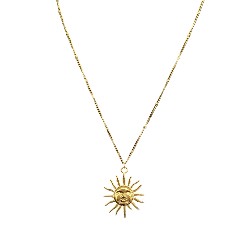 Gold sun-shaped pendant necklace on a black surface