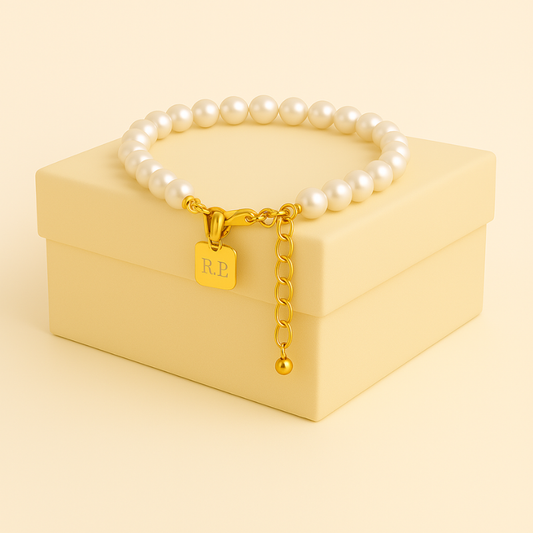 Round Pearl Titanium Steel Beaded Bracelet on cream box, showcasing pearls and gold detailing.