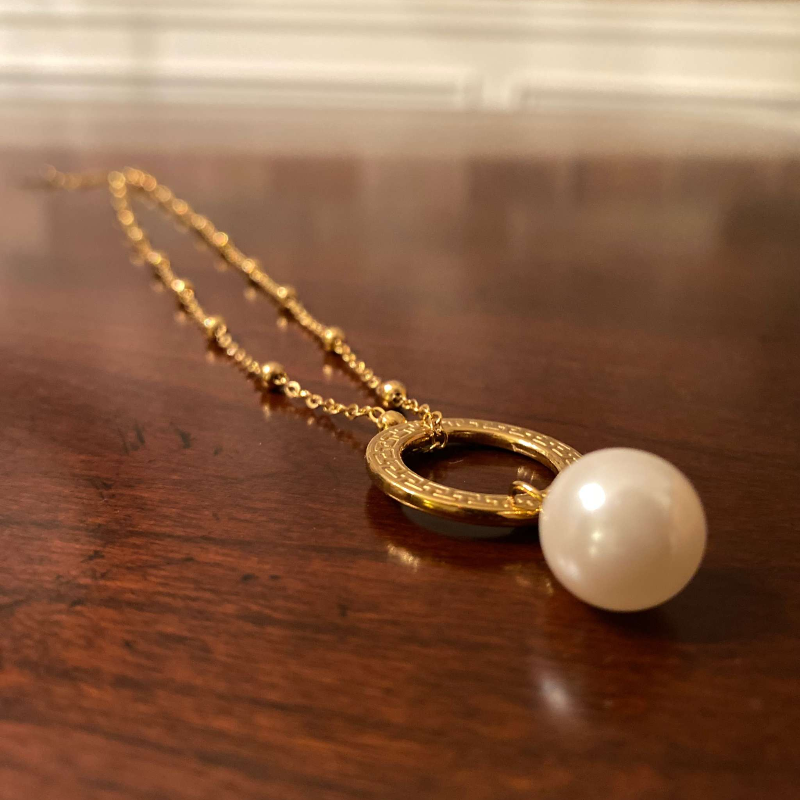 Elegant pearl necklace from the Enduring Grace Collection by NueJewelz on a wooden surface.