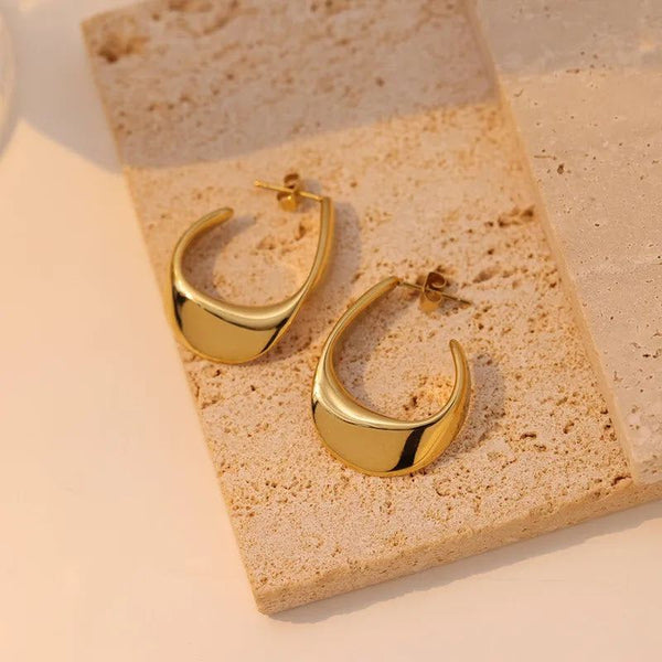 Stainless steel gold plated earrings on textured surface, elegant accessory.