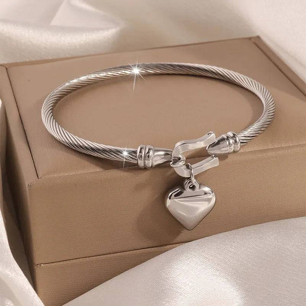 Elegant titanium steel bangle with heart-shaped pendant.