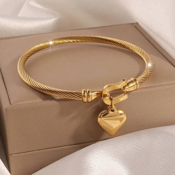 Gold-toned twisted cable bangle with heart pendant from Nue Jewelz.