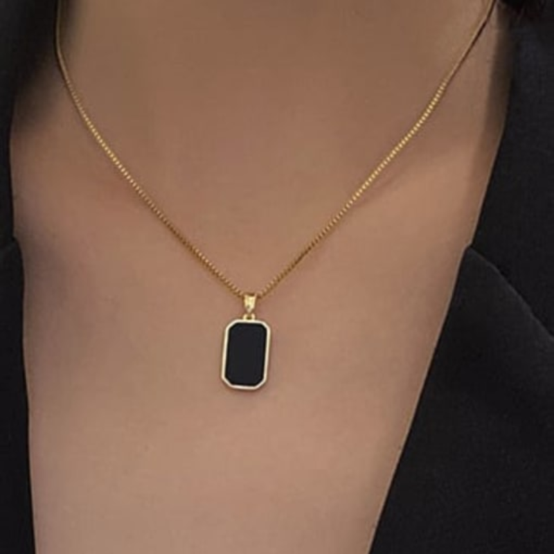 The Anchor Pendant black inlay titanium necklace on gold chain worn with black top