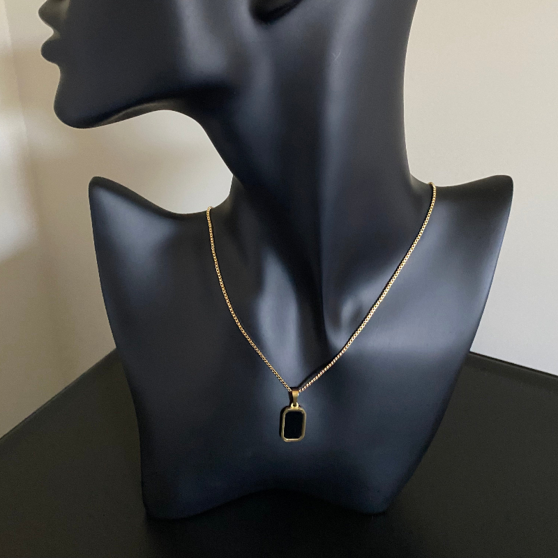 Necklace with a black pendant on a black mannequin bust against a neutral background