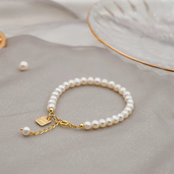 Round Pearl Titanium Steel Beaded Bracelet with gold chain and charm on neutral background.