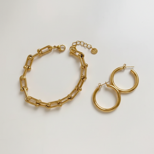 The Gold Everyday Essentials gold link bracelet and chunky hoop earrings set on white background